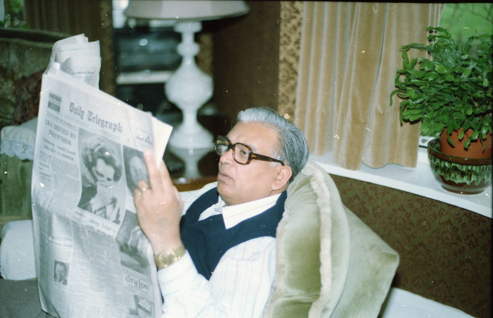 Ram Prashad Gupta reading the Daily Telegraph in an armchair in England, 1984