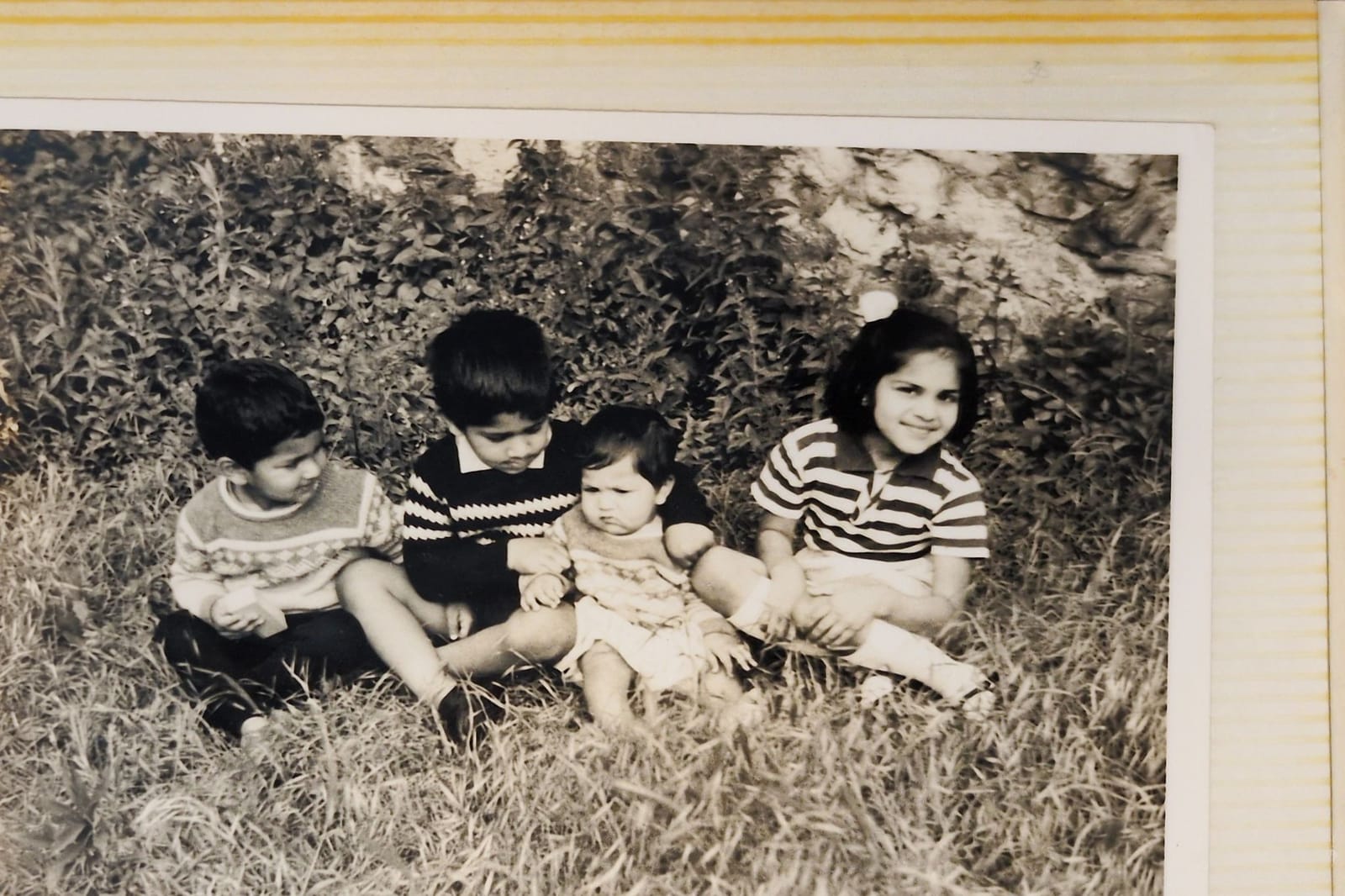 Four Indian children sitting on the grass, black and white, 1960s